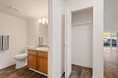 A white bathroom with a toilet, sink, and wooden floors.