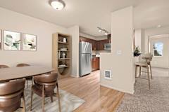 A kitchen with a refrigerator, dining table and chairs.