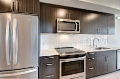 A modern kitchen with a stainless steel refrigerator and a white backsplash.