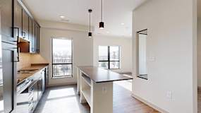 A kitchen with dark wooden cabinets, quartz countertops, a tile backsplash, an island, and a window over the kitchen sink.