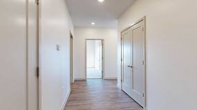 A hallway with a closet to the side, and an open door to a bedroom at the end.