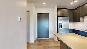 a kitchen with dark wood cabinets and stainless steel appliances next to a dark grey front door