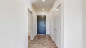 A hallway with a closet to the side, with a front door at the end.