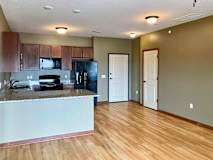 A kitchen with dark wooden cabinets and granite countertops open to a dining area with hardwood-style flooring.