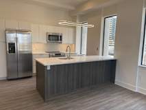 a kitchen with a large island and a stainless steel refrigerator at Sky On Main Apartments, Missouri, 64105