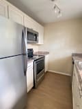 A kitchen with a refrigerator, microwave, oven, and cabinets.