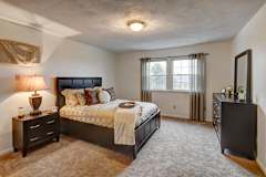 A bedroom with a large bed and a nightstand with a lamp.