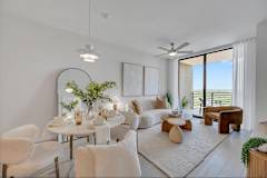 A modern living room with a dining table set for two and a view of the balcony.