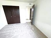 A bedroom with a carpeted floor and a brown door.