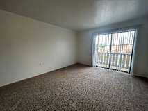A living room with a carpeted floor and a window with bars.
