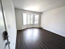 Spacious empty living room with bay window and laminate flooring at Charter Oaks Apartments, Davison, 48423