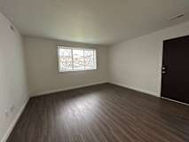Spacious living room with vinyl plank flooring and a window.