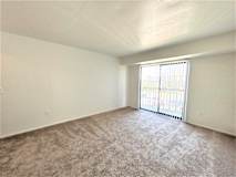 A living room with a carpeted floor and a window with blinds.