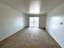 A living room with a carpeted floor and a sliding glass door.