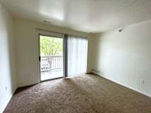 A living room with a carpeted floor and a sliding glass door leading to a balcony.