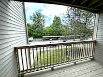 A view from a balcony looking out at a parking lot and trees.