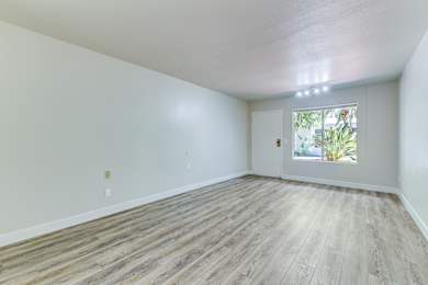 Empty room with wooden flooring and a window.