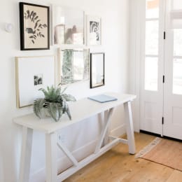 a white desk with a plant and pictures on the wall