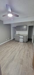 A room with a ceiling fan and a bed in the background. at Villa La Paz Apartments, California, 90706