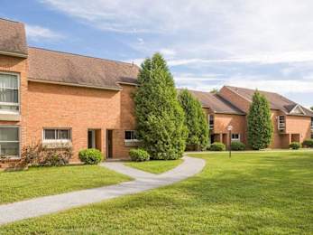 A building with a red brick exterior and a green lawn in front.