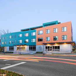 A modern multi-story building with a mix of blue and orange panels.