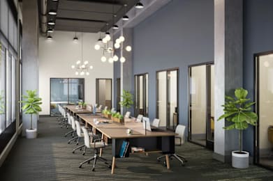 A modern office space with a long table and chairs, potted plants, and hanging lights.