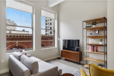 a living room with a couch and a tv and a window at Textile Apartments, Cincinnati