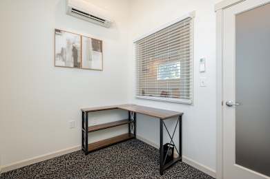 A room with a window, a bench, and a painting on the wall.