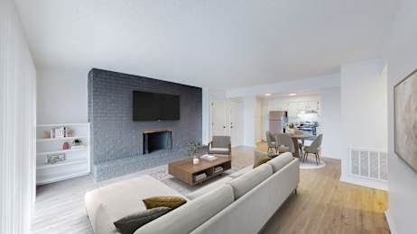 A modern living room with a grey couch and a fireplace.