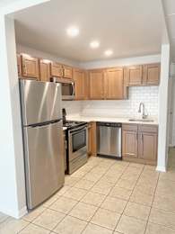 Compact kitchen with light wood cabinets and tile floor at Fox Run Apartments, Illinois