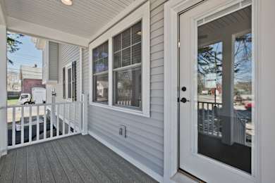 A white door is open to a deck with a railing.