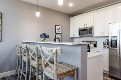 A kitchen with a white counter and bar stools.