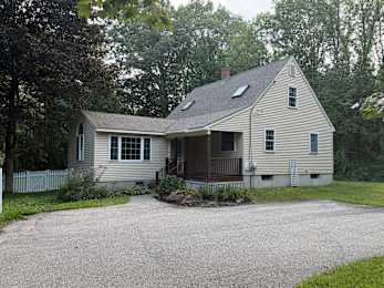 A house with a grey siding and a white picket fence.