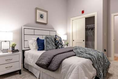 A bedroom with a bed, nightstand, and a picture on the wall.
