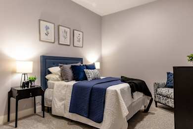 A bedroom with a bed, a nightstand, and a chair.