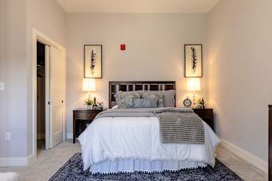 A bedroom with a large bed and two wall lamps.