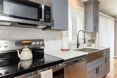 A modern kitchen with a black stove top and a black microwave above it.