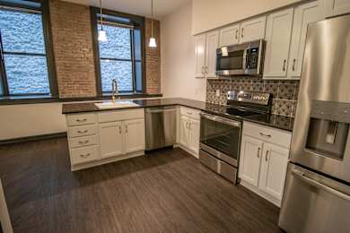 A kitchen with stainless steel appliances and wooden floors.
