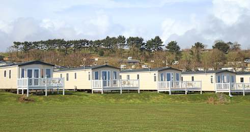 A row of mobile homes are lined up in a field.