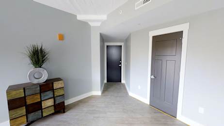 a hallway with a grey door and a vase on a dresser
