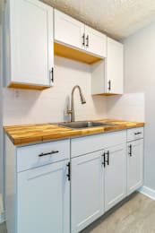 A kitchen with white cabinets and a wooden countertop.