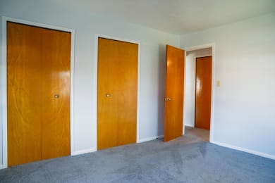 three doors in a room with carpet and white walls