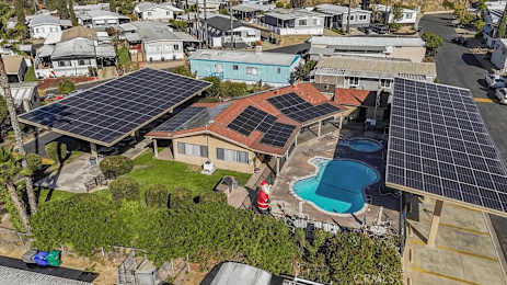 A house with solar panels on the roof and a pool in the backyard.