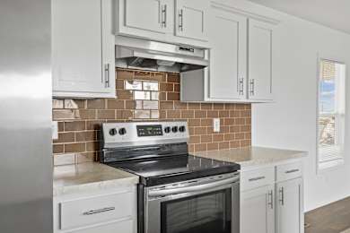 A modern kitchen with a stove top oven and white cabinets.