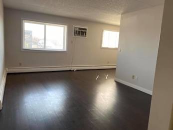 A room with a window and a vent on the wall.