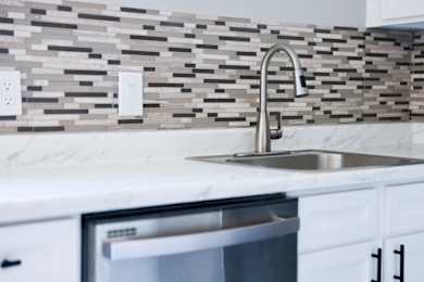 A modern kitchen with a marble countertop and a stainless steel sink.