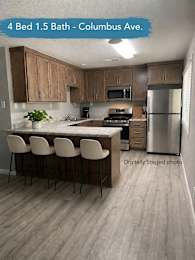 A kitchen with a bar stool and a refrigerator.