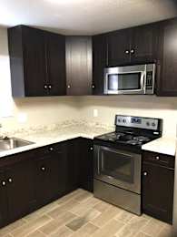 Kitchen with dark wood cabinets and granite countertops at OSM Properties Homes & Apartments, California
