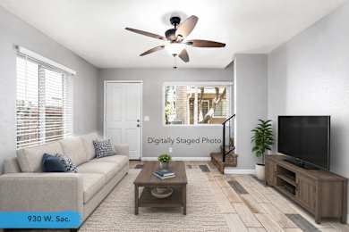 A living room with a couch, a coffee table, a ceiling fan, and a television.