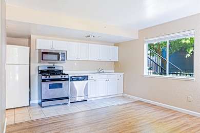 Open kitchen with white cabinetry and tile flooring at Redwood Cove Apartments, Chico